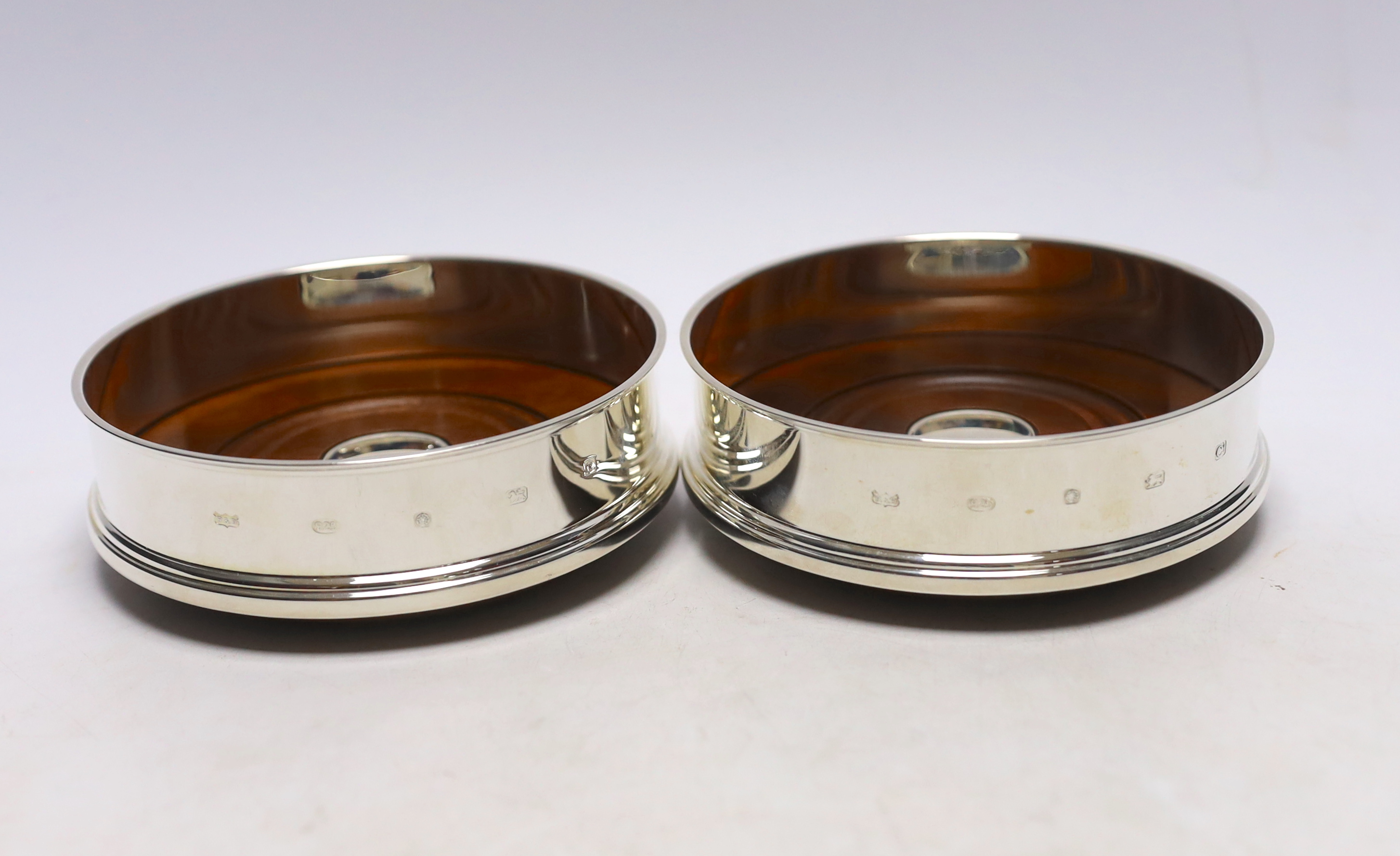 A pair of Elizabeth II silver mounted wine coasters, with turned wooden bases, Roberts & Dore, Sheffield, 2002, diameter 12.4cm, each individually boxed.